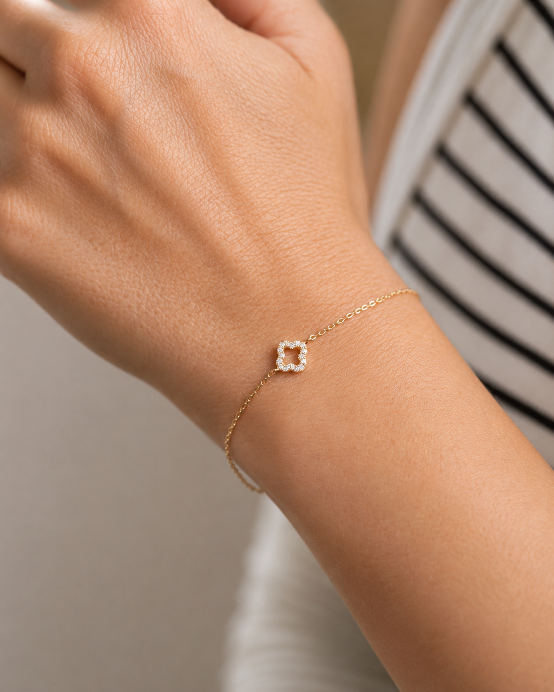 PamelaNor Armband aus vergoldetem 925 Silber mit feinem Kleeblatt-Anhänger, natürlich am Handgelenk getragen.