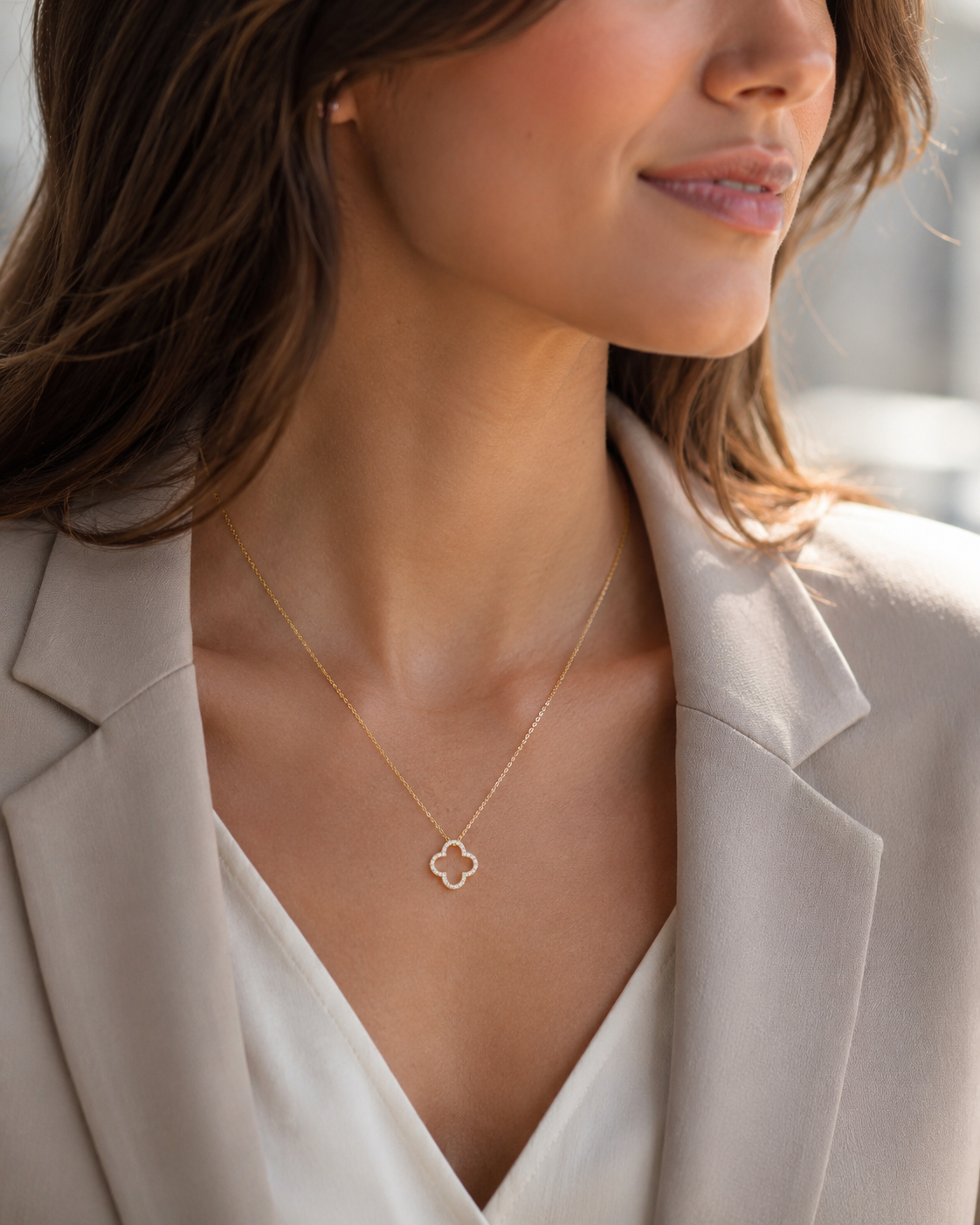 PamelaNor Elegante goldfarbene Halskette mit Kleeblatt-Anhänger zu Blazer und heller Bluse im modernen Look.