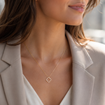 PamelaNor Elegante goldfarbene Halskette mit Kleeblatt-Anhänger zu Blazer und heller Bluse im modernen Look.
