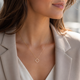 PamelaNor Elegante goldfarbene Halskette mit Kleeblatt-Anhänger zu Blazer und heller Bluse im modernen Look.