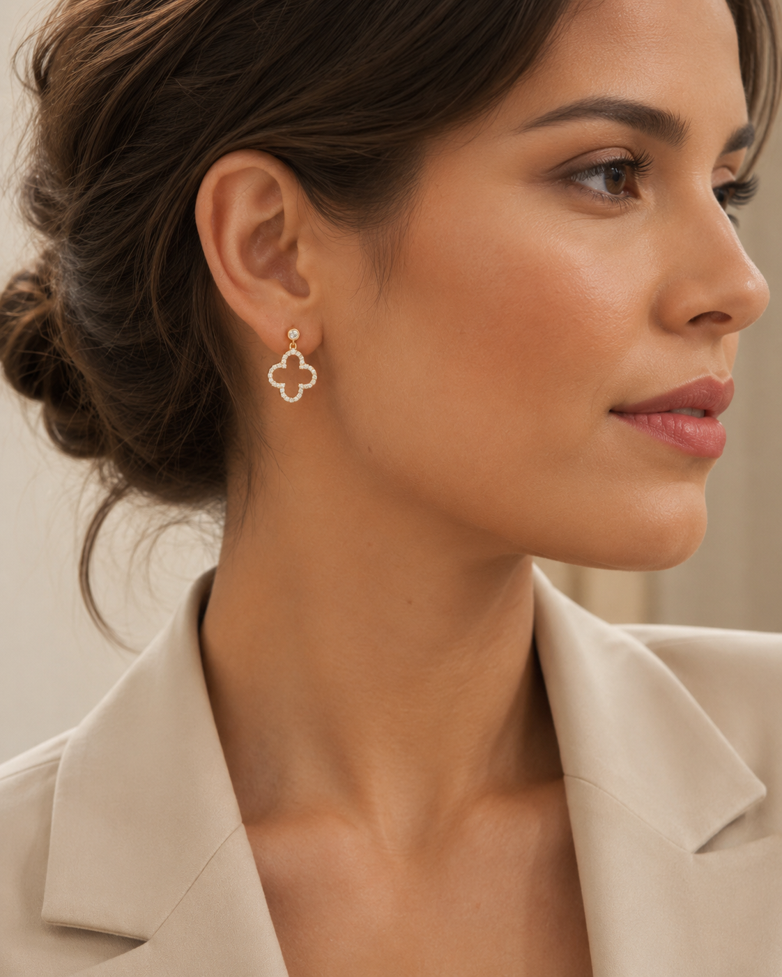 PamelaNor Ohrhänger aus vergoldetem 925 Silber mit funkelndem Kleeblatt-Design, elegant zu hellem Blazer getragen.
