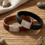 „Zwei glatte Herren-Lederarmbänder in Braun und Schwarz mit breitem Edelstahl-Magnetverschluss von Son of Noa auf rustikalem Holztisch.“