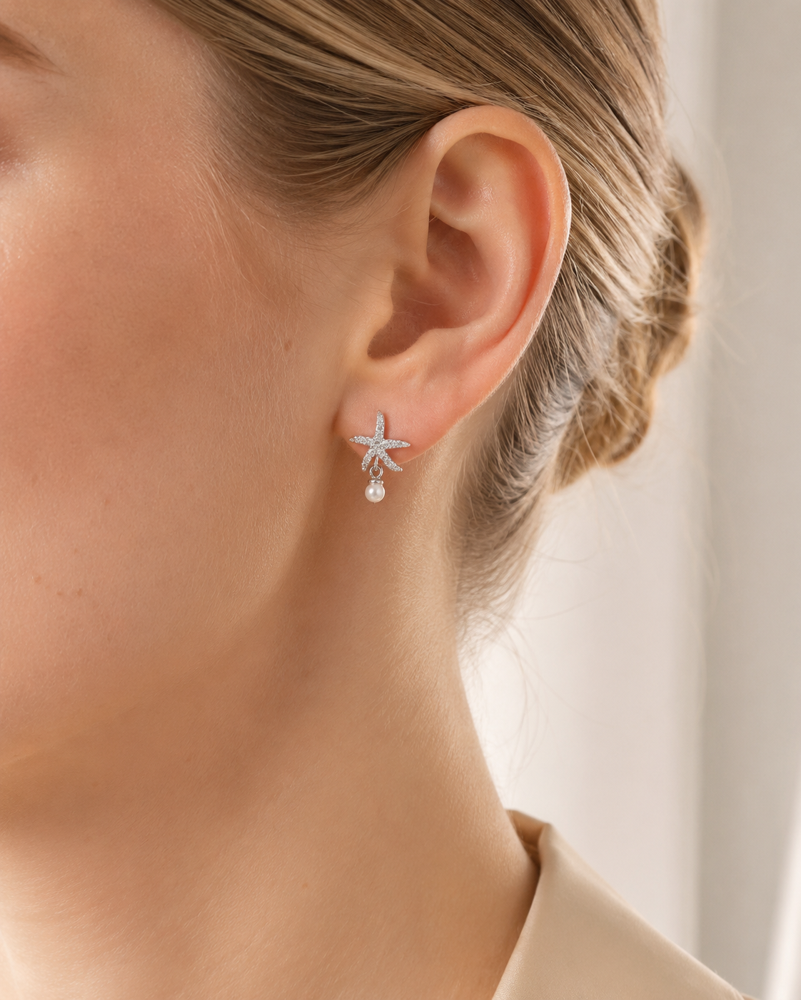 SelinaNor Ohrstecker aus 925 Sterling Silber mit Seestern-Motiv und kleiner Perle, getragen im cleanen Beauty-Look.