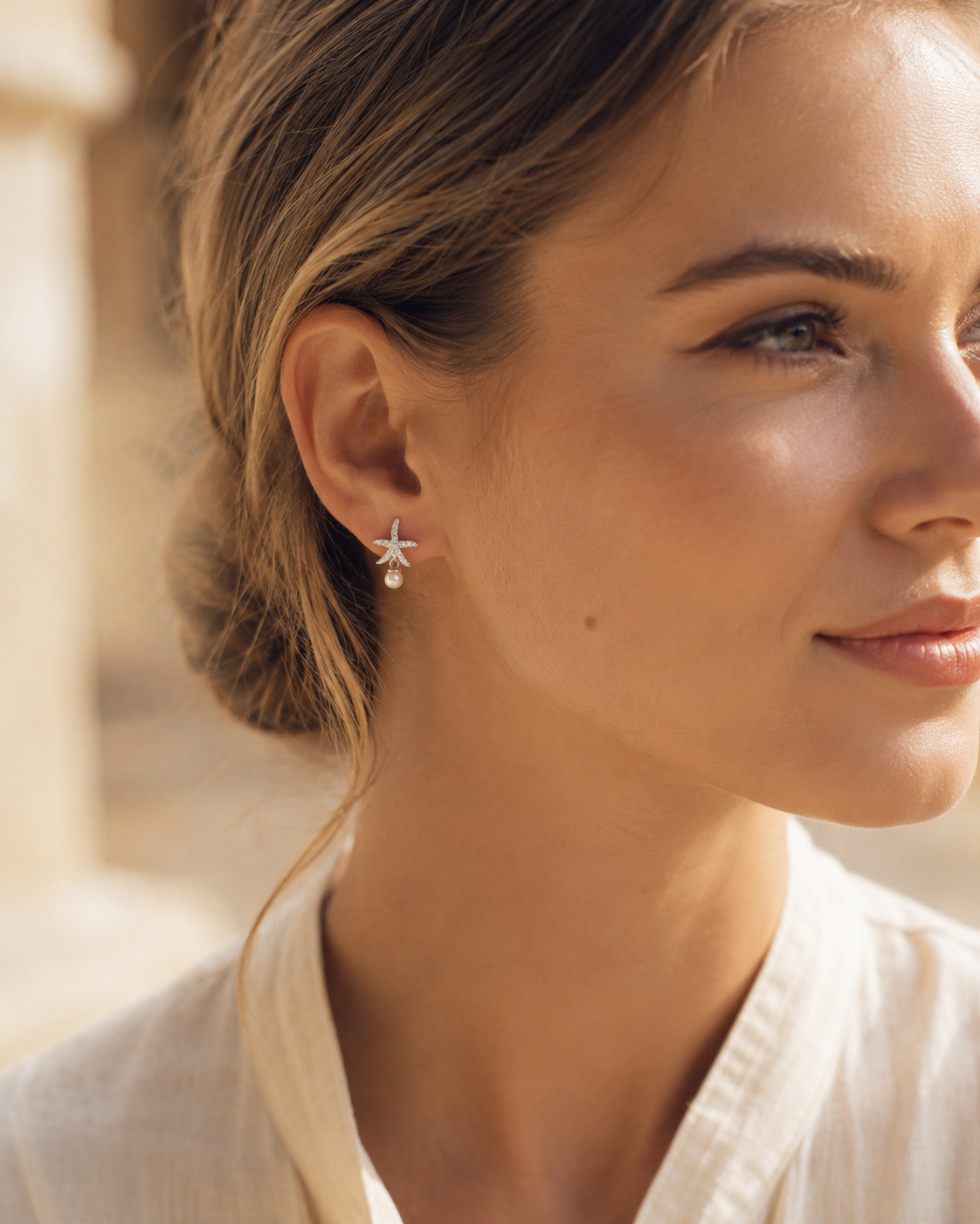 Funkelnder Seestern-Ohrstecker aus 925 Sterling Silber mit kleiner Perle, getragen in warmer natürlicher Lichtstimmung.
