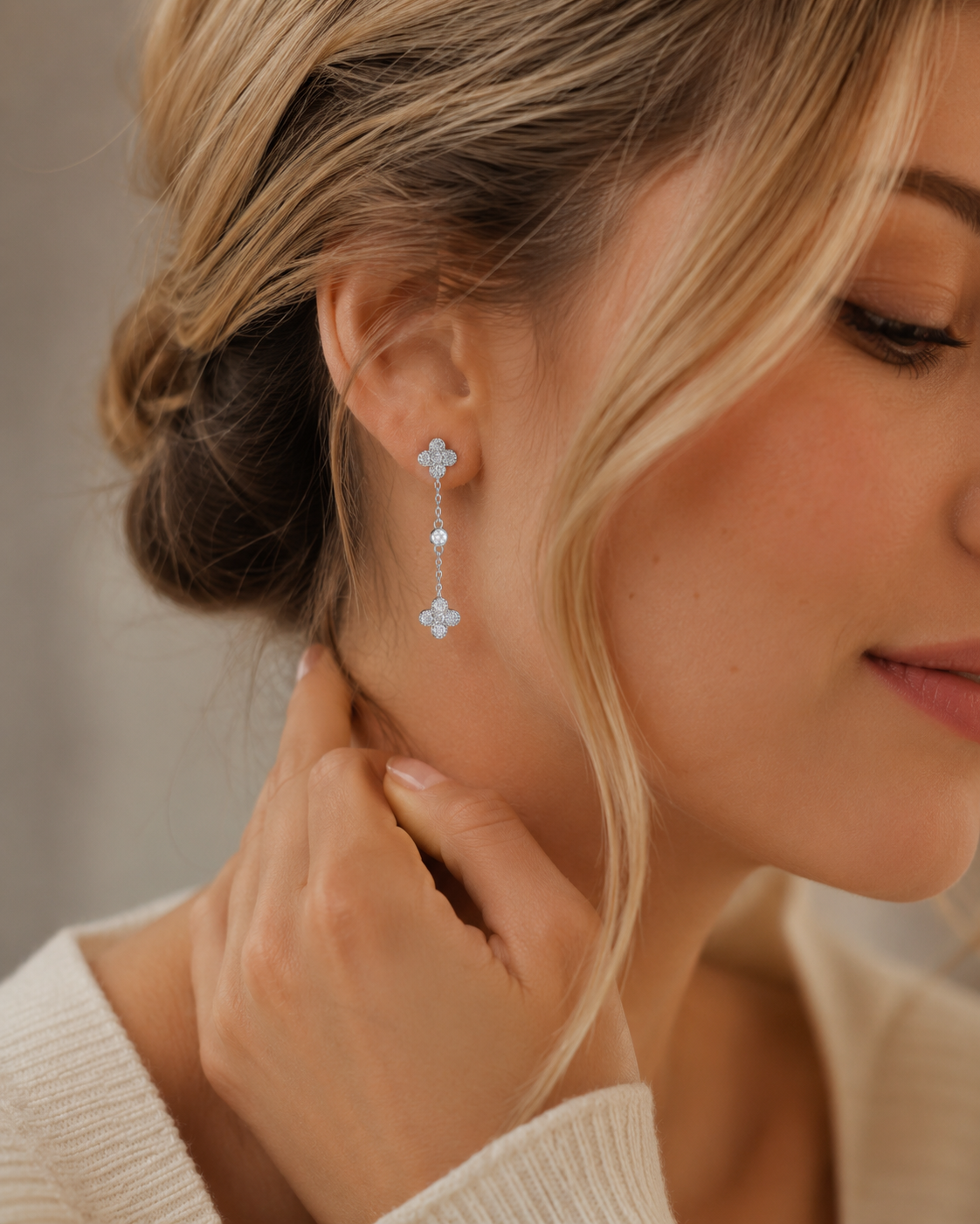 SigneNor Eleganter Ohrhänger aus 925 Sterling Silber mit zarten Kleeblatt-Details, getragen im femininen Lifestyle-Look mit hellem Strick.