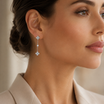 SigneNor Funkelnder Ohrhänger aus 925 Sterling Silber mit Kleeblatt-Motiven, kombiniert mit hellem Blazer im modernen Editorial-Look.