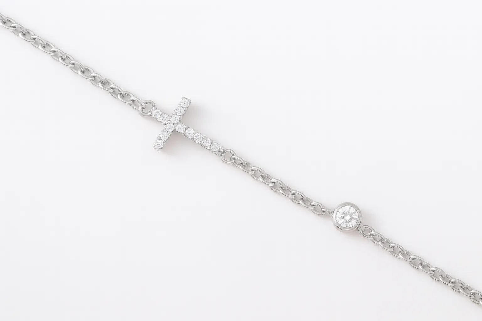 Feines Damenarmband aus 925 Sterling Silber mit seitlich eingearbeitetem Kreuzanhänger und rundem Zirkonia-Solitär auf weißem Hintergrund.