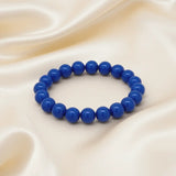 Ein Armband aus blauen Perlen auf einem glatten, hellen Stoff.