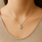 Frau trägt eine feine Silberkette mit rundem Anhänger aus Aqua Chalcedon Cabochon – eleganter, minimalistischer Schmuck mit sanft schimmerndem Edelstein in zartem Blaugrün