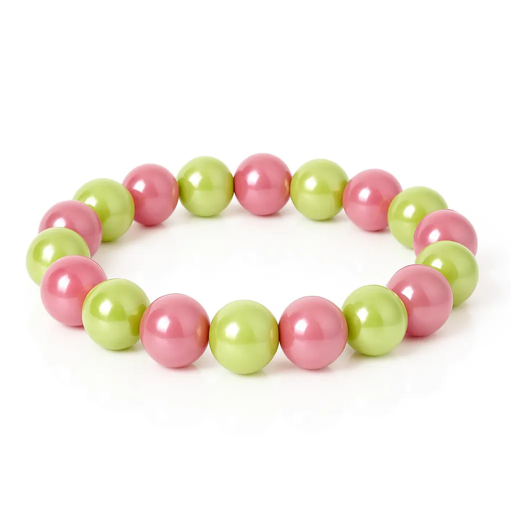 Ein Armband mit abwechselnd pinken und grünen glänzenden Perlen liegt auf einem weißen Hintergrund.