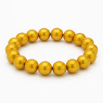 Goldfarbenes Perlenarmband aus glänzenden, runden Perlen auf elastischem Band, kreisförmig angeordnet vor weißem Hintergrund.