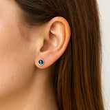 Nahaufnahme eines Ohrs mit einem eleganten Ohrstecker aus 925er Silber und rundem Labradorit-Cabochon, der in schimmernden Blau- und Grüntönen leuchtet.