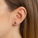 Nahaufnahme eines weiblichen Ohrs mit einem eleganten Ohrstecker aus 925er Sterlingsilber, besetzt mit einem runden orangefarbenen Mondstein-Cabochon. Der warme Glanz des Steins verleiht dem Schmuckstück eine natürliche, dezente Eleganz.