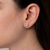 Nahaufnahme eines Ohrs mit einem eleganten silbernen Ohrstecker, besetzt mit einem zartgrünen Prehnit-Cabochon in runder Fassung.