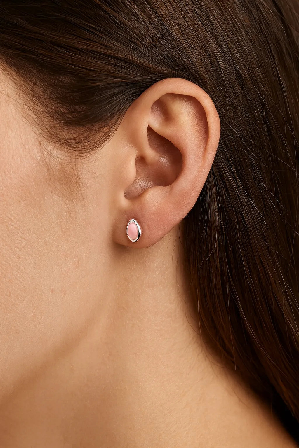 Nahaufnahme eines Ohrs mit einem eleganten Ohrstecker aus Sterlingsilber, gefasst mit einem zarten, rosafarbenen Rosenquarz-Cabochon in marquiseförmigem Schliff. Der sanfte Glanz des Steins verleiht dem Schmuckstück eine feminine und edle Ausstrahlung.