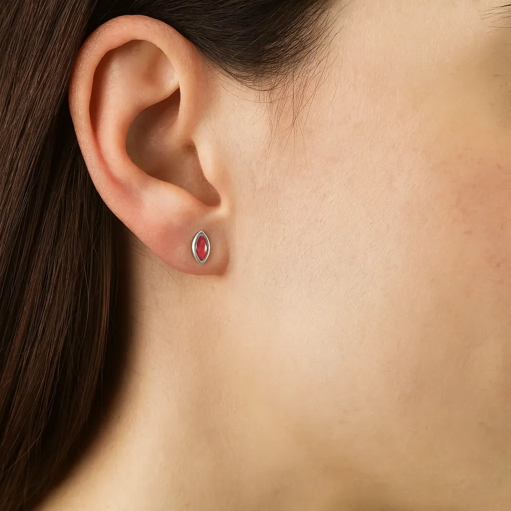 Nahaufnahme eines Ohrs mit einem feinen Ohrstecker in Blattform aus Sterlingsilber, besetzt mit einem rosaroten Turmalin-Cabochon. Der zarte Glanz des Steins verleiht dem Schmuckstück eine elegante und feminine Note.