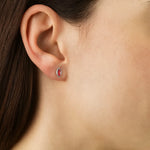 Nahaufnahme eines Ohrs mit einem feinen Ohrstecker in Blattform aus Sterlingsilber, besetzt mit einem rosaroten Turmalin-Cabochon. Der zarte Glanz des Steins verleiht dem Schmuckstück eine elegante und feminine Note.