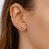 Nahaufnahme einer Frau in Seitenansicht mit einem kleinen, marquiseförmigen Peridot-Ohrring aus Silber am Ohrläppchen. Der grüne Edelstein schimmert dezent im Licht, und die natürliche Haut- und Haarfarbe der Frau sind weich ausgeleuchtet.
