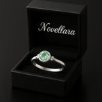 Eleganter Silberring mit rund facettiertem grünem Edelstein (4 mm) in Zargenfassung, präsentiert in geöffneter schwarzer Schmuckbox mit Novellara Logo – hochwertiger Damenring als Geschenk oder Verlobungsring.
