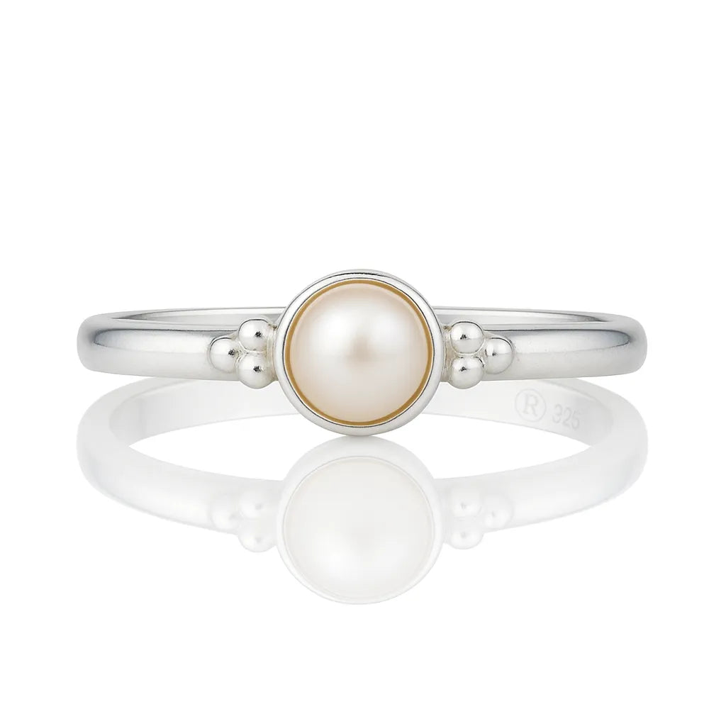 Feiner Damenring aus 925 Silber mit runder Perle und dekorativen Silberkügelchen, liegend auf glänzend weißem Untergrund mit klarer Spiegelung, hochwertiges Schmuckprodukt in Nahaufnahme.