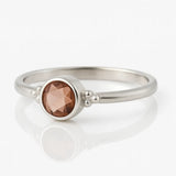 Damenring aus Sterling Silber mit rundem facettierten Rauchquarz in Zargenfassung – filigraner Silberring mit braunem Edelstein auf weißem spiegelnden Hintergrund, eleganter Schmuck für Frauen.
