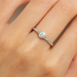 Eine Nahaufnahme einer Frauenhand zeigt einen eleganten Silberring am Ringfinger. Der Ring besitzt ein schlichtes, rundes Design mit einem klar facettierten Zirkonia-Stein in der Mitte, der in einer glatten Fassung eingefasst ist. Der Fokus des Bildes liegt auf dem Ring, der auf der Haut leicht glänzt und das Licht fein reflektiert.
