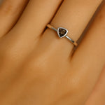 Nahaufnahme einer Frauenhand mit einem eleganten Silberring am Ringfinger. Der Ring trägt einen dreieckig facettierten Rauchquarz in warmer, brauner Farbe, der in einer glatten Fassung eingefasst ist. Der Fokus liegt klar auf dem Ring und dem glänzenden Edelstein, während der Hintergrund sanft verschwimmt.
