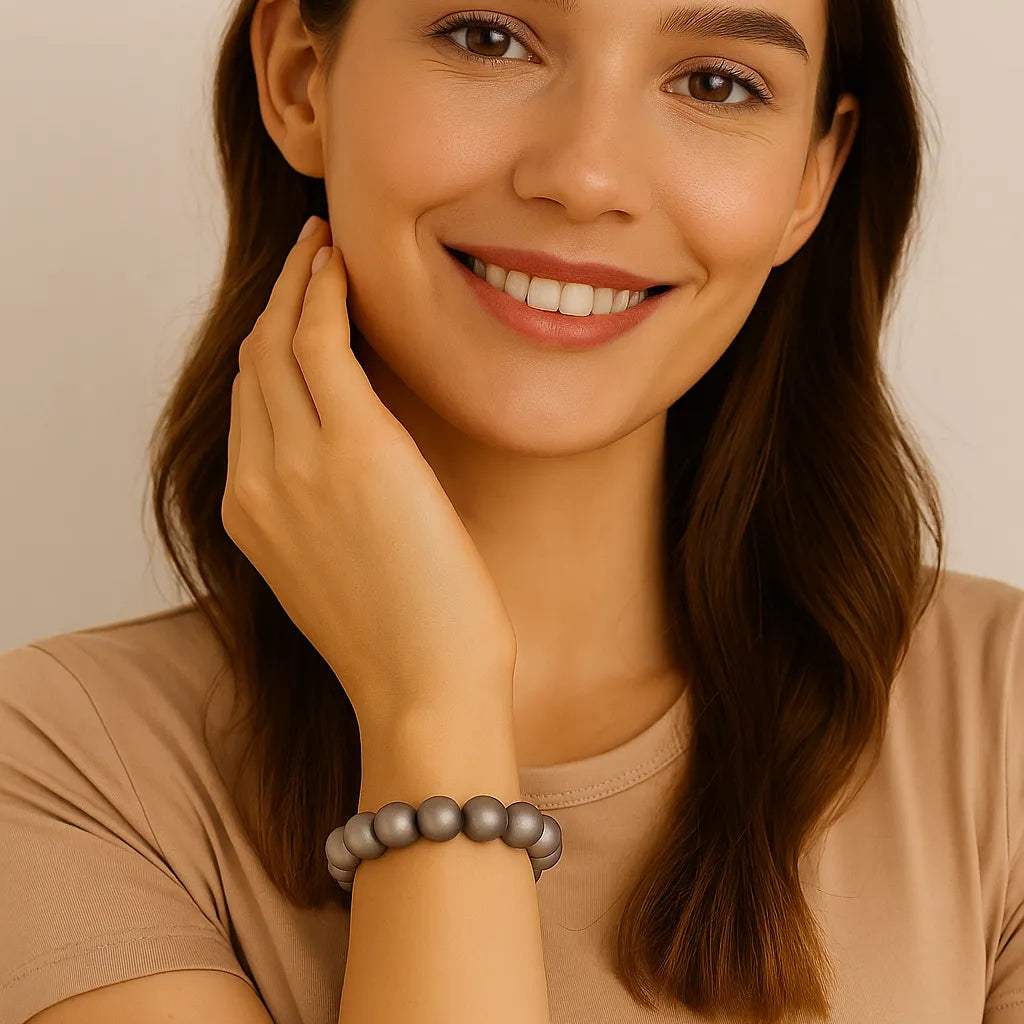 Junge Frau mit schulterlangen braunen Haaren trägt ein elastisches Armband aus silbergrauen Perlen am Handgelenk