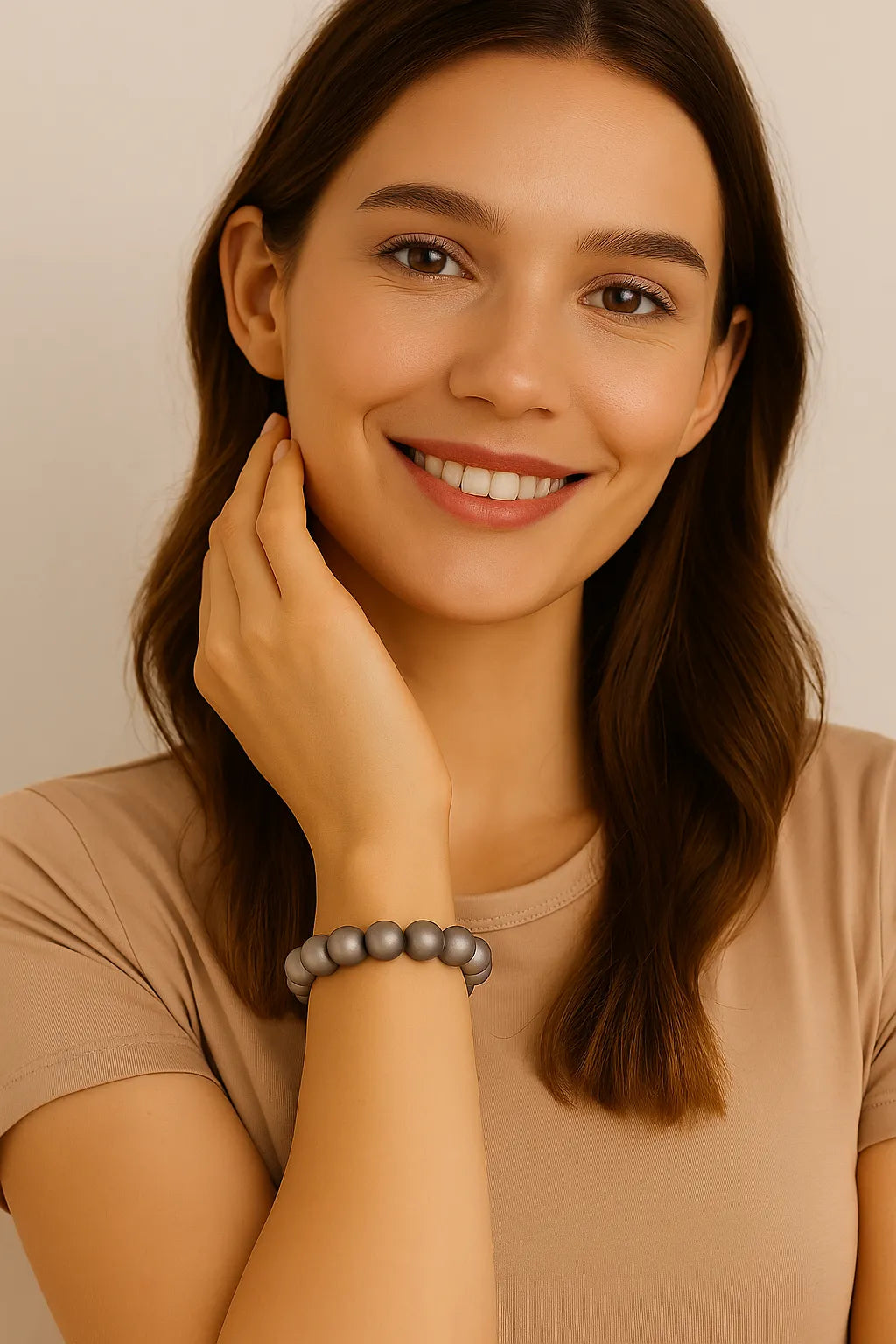 Junge Frau mit schulterlangen braunen Haaren trägt ein elastisches Armband aus silbergrauen Perlen am Handgelenk