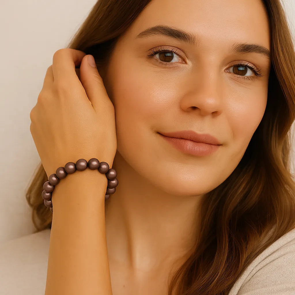 Junge Frau mit langen braunen Haaren trägt ein Armband aus schimmernden, braunen Perlen am Handgelenk