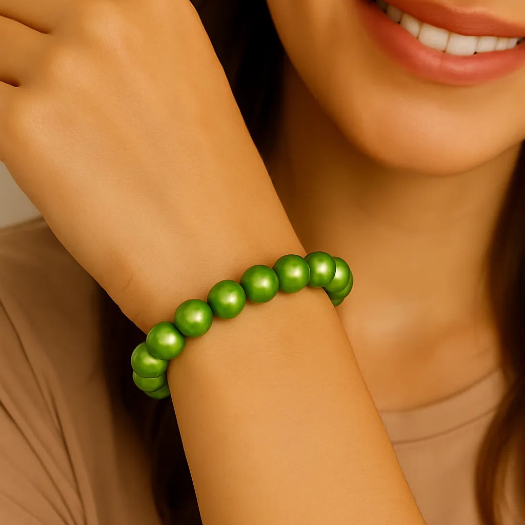 Nahaufnahme einer lächelnden Frau mit hellem Teint, die ein elastisches Armband aus glänzenden, hellgrünen Perlen am rechten Handgelenk trägt.