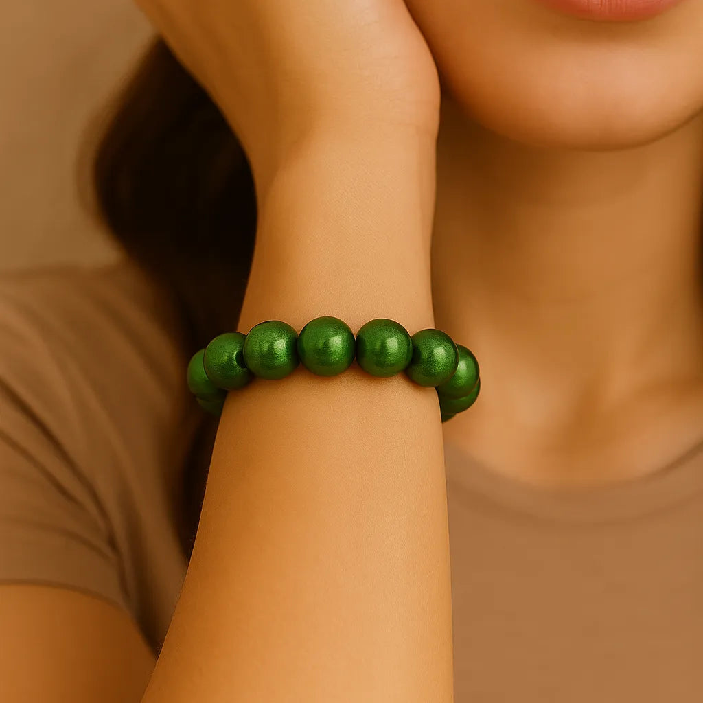 Nahaufnahme einer Frau, die ein elastisches 3D Wonderperlen Armband mit glänzenden, smaragdgrünen Perlen am Handgelenk trägt.