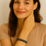 Eine junge Frau mit mittellangen braunen Haaren trägt ein elastisches Armband aus dunkelblauen, glänzenden Perlen am Handgelenk