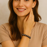 Junge Frau mit braunen Haaren trägt ein elastisches Armband aus dunkelgrauen Perlen am Handgelenk