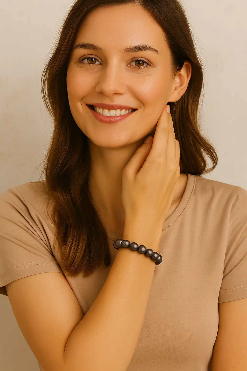 Junge Frau mit braunen Haaren trägt ein elastisches Armband aus dunkelgrauen Perlen am Handgelenk