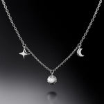 "Feine Damen-Halskette aus Silber mit polierten Anhängern Stern, Sonne und Halbmond – eleganter Symbolschmuck auf schwarzem Hintergrund"
