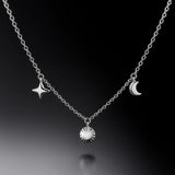 "Feine Damen-Halskette aus Silber mit polierten Anhängern Stern, Sonne und Halbmond – eleganter Symbolschmuck auf schwarzem Hintergrund"
