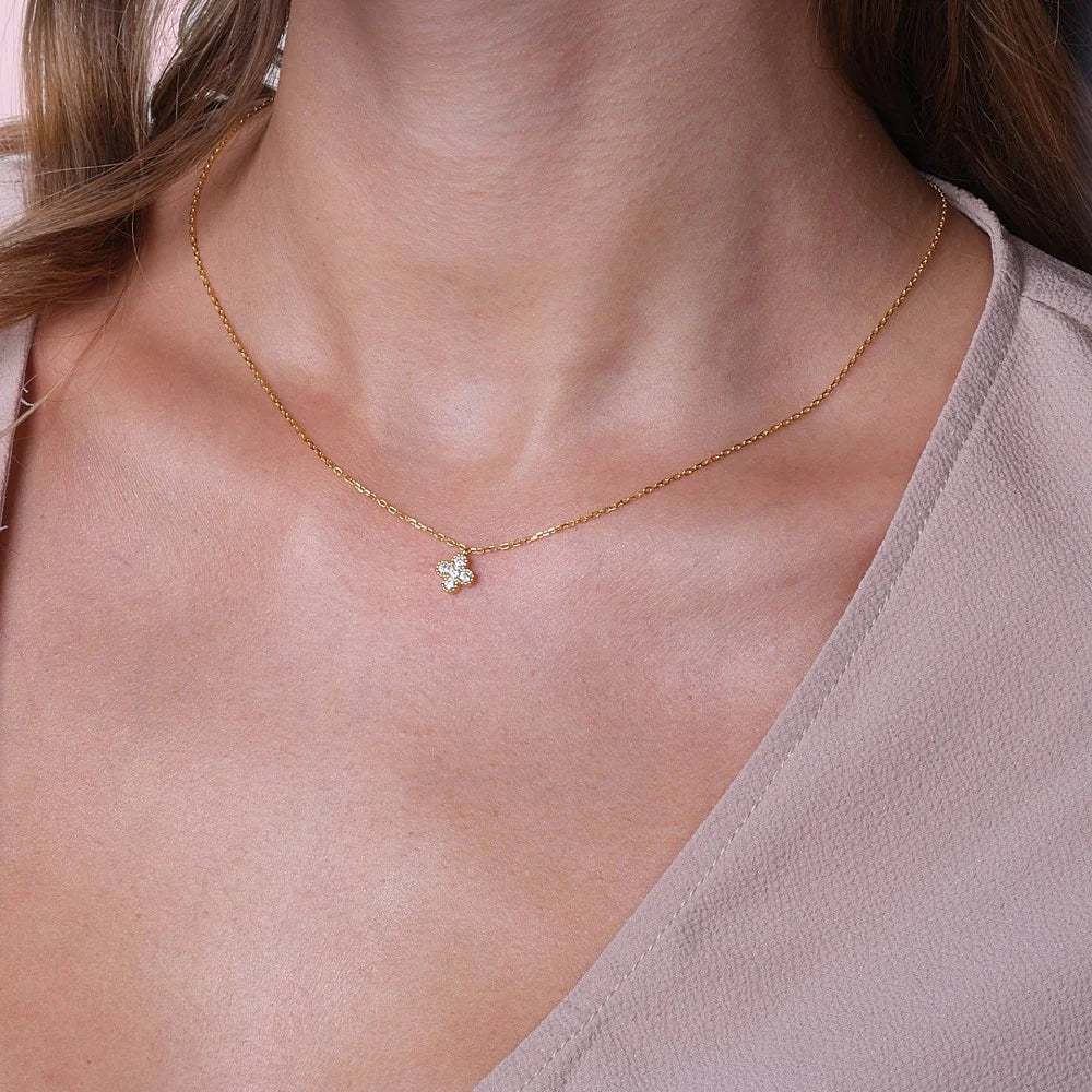 SigneNor Halskette aus 925 Silber 18 Karat vergoldet mit funkelndem Kleeblatt-Anhänger an elegantem Dekolleté.