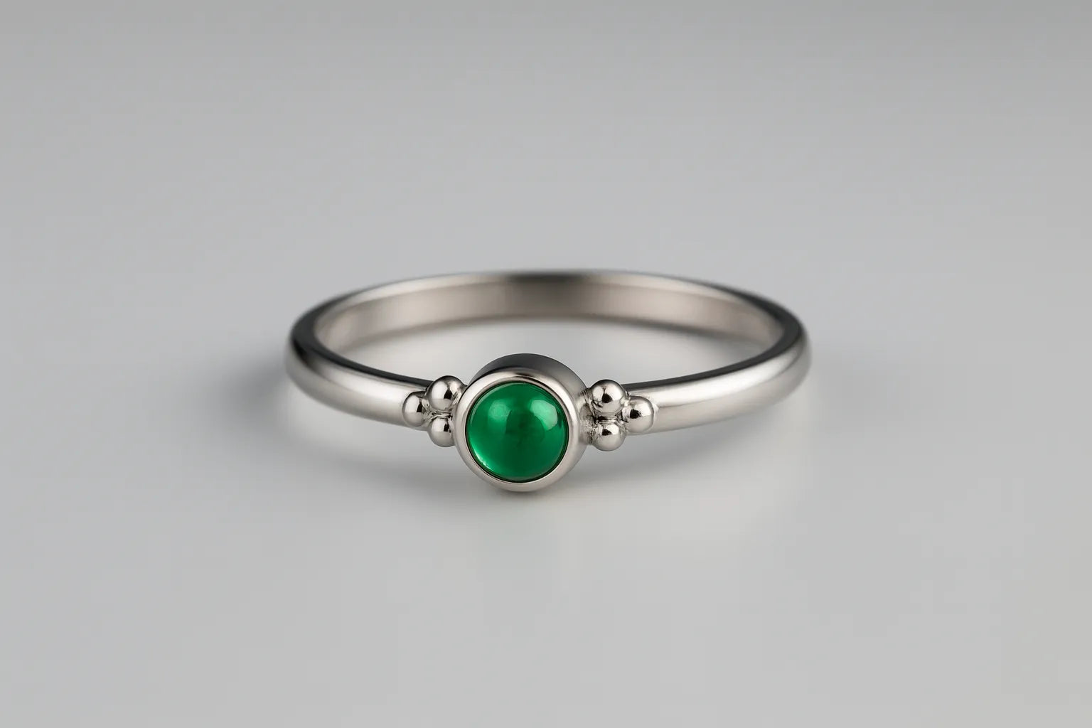 Eleganter Damenring aus 925 Sterling Silber mit rundem Smaragd-Cabochon in leuchtendem Grün, gefasst in einer Zargenfassung mit feinen Silberkügelchen, edel inszeniert im Studio auf hellem Hintergrund als hochwertiger Edelsteinschmuck.
