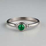 Eleganter Damenring aus 925 Sterling Silber mit rundem Smaragd-Cabochon in leuchtendem Grün, gefasst in einer Zargenfassung mit feinen Silberkügelchen, edel inszeniert im Studio auf hellem Hintergrund als hochwertiger Edelsteinschmuck.
